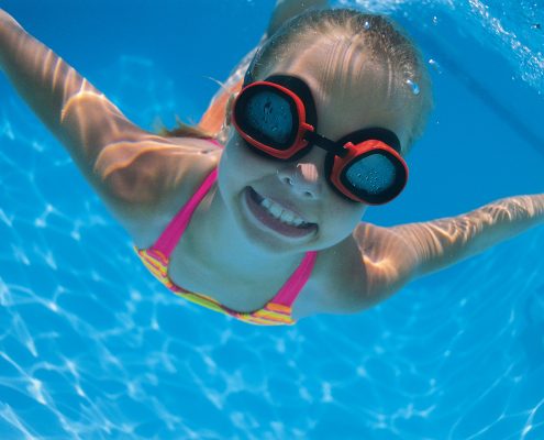 Girl with goggles swimming underwater