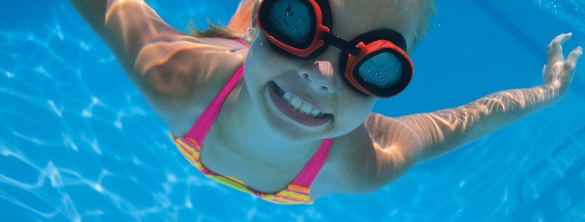 Girl with goggles swimming underwater